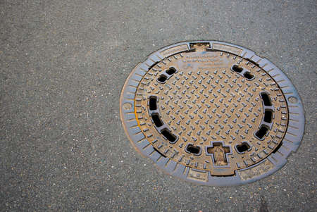 Manhole cover on garden pavement in spring time