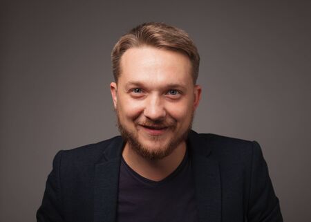 Handsome man smiling over dark background looking at camera.の写真素材