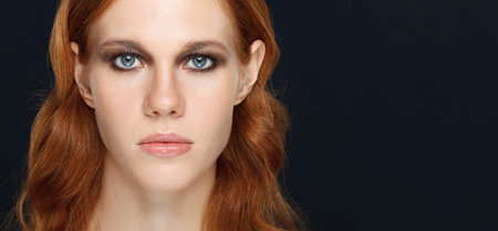 Woman portrait with serious emotion over dark background.の写真素材