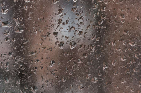 Raindrops on the surface of a dirty window glass. Rainy background with water drops on window glassの写真素材