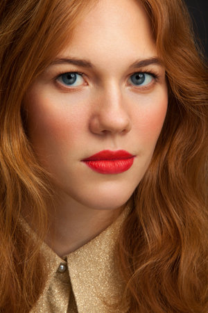 Elegantly dressed young red-haired girl looks at the camera. Portrait of a young woman.