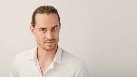 Young blonde bearded man looking in camera. Portrait of caucasian guy with trendy hairdo isolated over a white studio background with copy spaceの写真素材