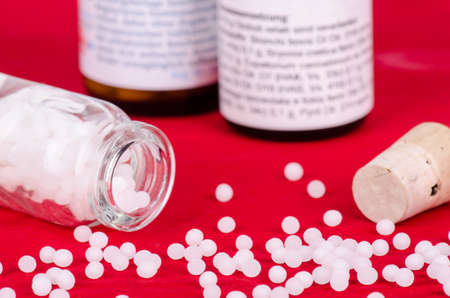 homeopathic globules on a red wooden background, selective focusの写真素材