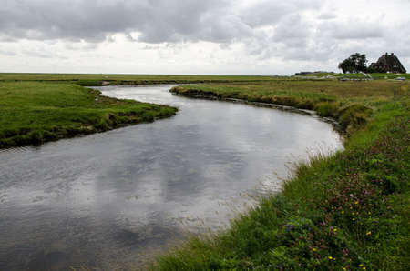 creek in the grassland with cottage in the background