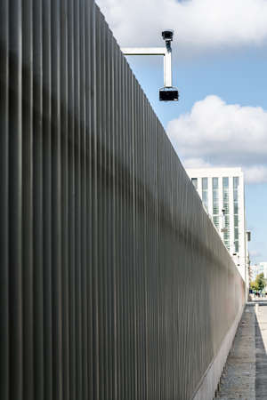 surveillance monitoring security camera on a fence with blue skyの写真素材