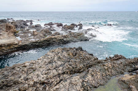 rocky coastline, natural volcanic rock, foaming water