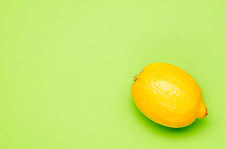 one yellow lemon on a green backgroundの写真素材