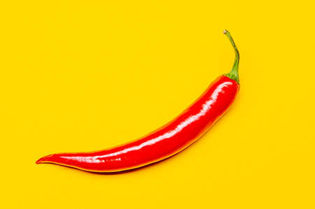 one red chili on a yellow backgroundの写真素材