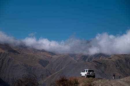 Caucasus, Georgia, Tusheti region, Omalo. An off-road car is park in front of a landscape view of caucasus mountains in Georgiaの写真素材