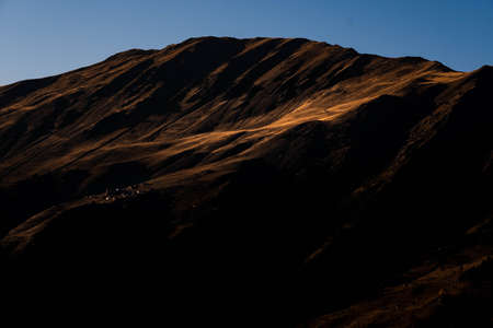 Caucasus, Georgia, Tusheti region, Omalo. A village on a mountainside is lit by the setting sun in the Tusheti region.の写真素材