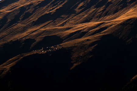 Caucasus, Georgia, Tusheti region, Omalo. A village on a mountainside is lit by the setting sun in the Tusheti region.の写真素材