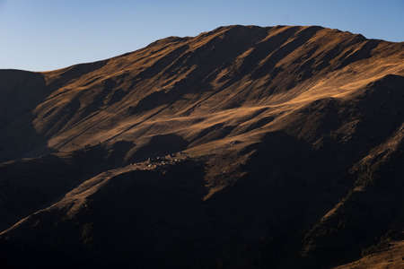Caucasus, Georgia, Tusheti region, Omalo. A village on a mountainside is lit by the setting sun in the Tusheti region.の写真素材