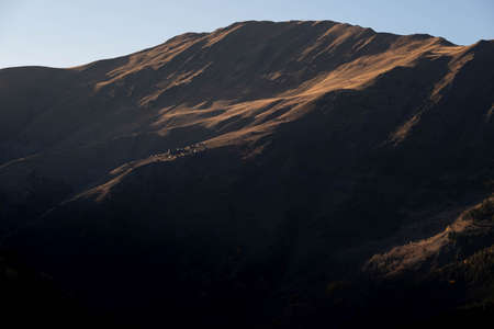 Caucasus, Georgia, Tusheti region, Omalo. A village on a mountainside is lit by the setting sun in the Tusheti region.の写真素材