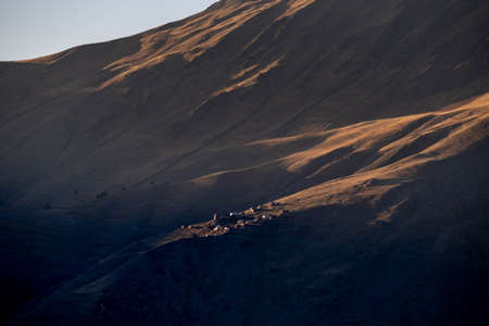 Caucasus, Georgia, Tusheti region, Omalo. A village on a mountainside is lit by the setting sun in the Tusheti region.の写真素材