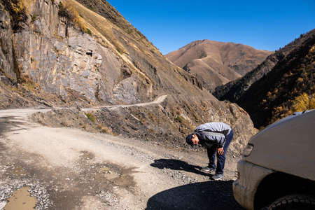 Caucasus, Georgia, Tusheti region, Omalo. A man repairs a car on the road to Omalo - Tusheti with mountains in the backgroundのeditorial素材