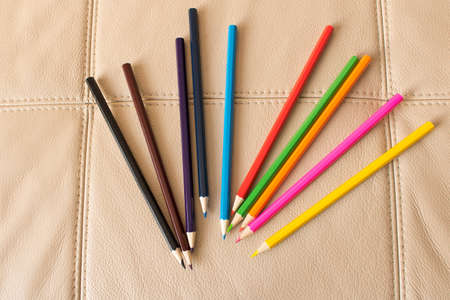 A set of colored pencils on a leather sofa backgroundの写真素材