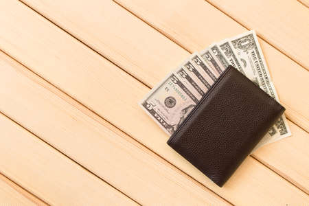 Leather wallet with dollars on wooden table backgroundの写真素材