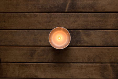 Burning candle on the background of wooden table. The view from the topの写真素材