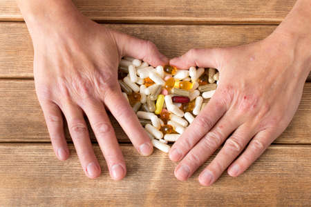Hands of the girl with atopic dermatitis with tablets . On the background of wooden table .の写真素材