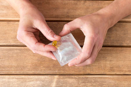 The choice between a condom and a pill . Hands with pill and a condom on the background .の写真素材