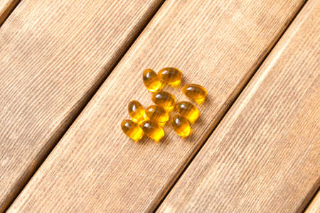 A few pills scattered on a wooden table . On a brown background .の写真素材