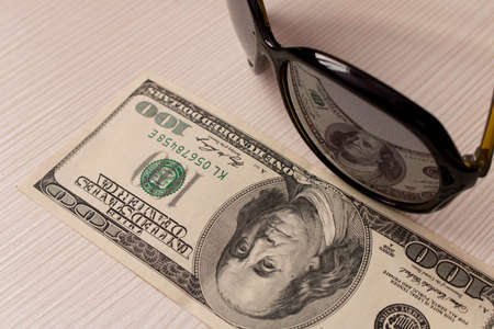 $ 100 is reflected in the glasses. On a beige backgroundの写真素材