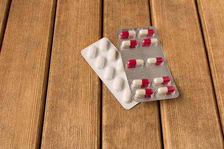 Two packs of pills on a wooden table .の写真素材