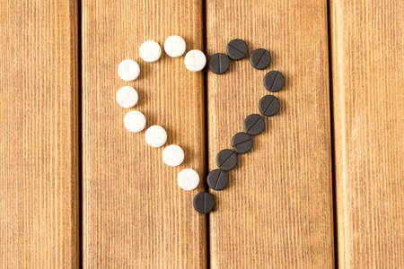 Heart-shaped pills on a wooden table の写真素材