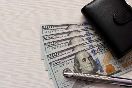 Hundred dollar bill and a leather wallet on the table .の写真素材