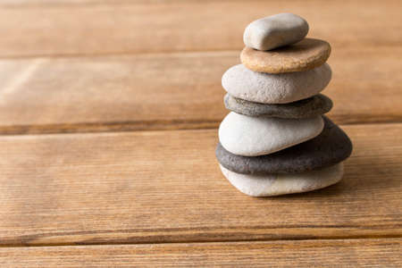 Pyramid of sea pebbles on a wooden table .の写真素材