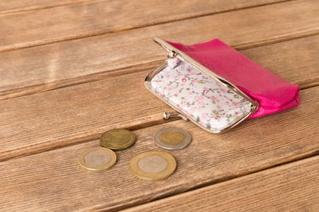 Wallet with coins on a wooden table . On wooden background .