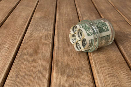 Dollar bills in a glass jar on a wooden table . The concept of poverty .の写真素材