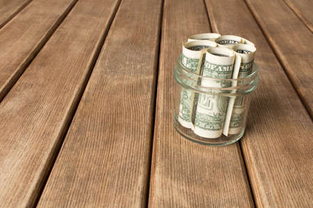 Dollar bills in a glass jar on a wooden table . The concept of poverty .の写真素材