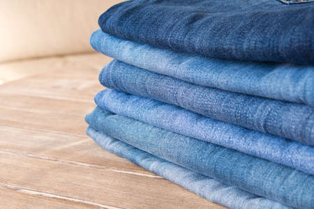 Various blue jeans on wooden background . Stack of jeans .