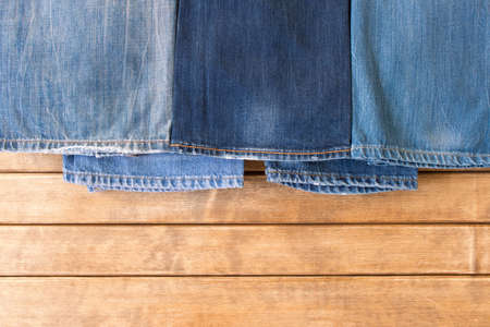 Various blue jeans on wooden background . The view from the top .の写真素材