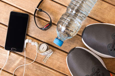 Gray running shoes and sports accessories on wooden background . Healthy lifestyle .