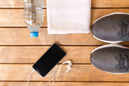Gray running shoes and sports accessories on wooden background . Healthy lifestyle .