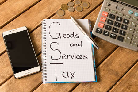 Good service and tax .  Notepad, pen, coins, smart phone on wooden background .の写真素材