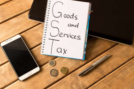 Good service and tax .  Notebook, pen, coins, smart phone on wood background .の写真素材