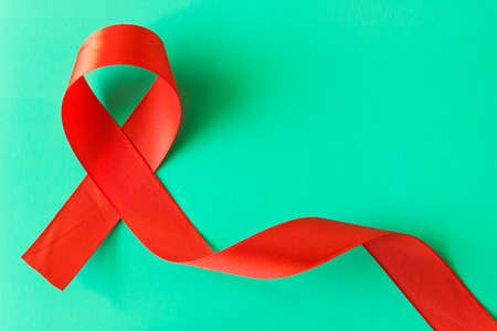 Red aids ribbon.  Isolated on turquoise background with empty space for text .