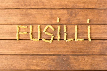 Uncooked fusilli pasta . On a wooden table . Italian food .の写真素材
