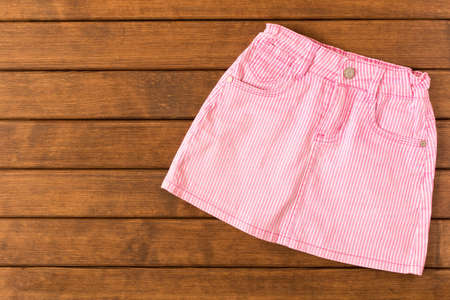 Fun skirt on a wooden background . Children's clothes. The view from the top