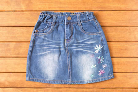 Children's denim skirt on wooden background . Children's clothes. Top view.