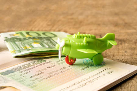 A small toy plane on a passport with a visa stamp and Euro banknotes. The concept of travel . Close...