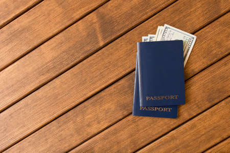Passports with banknotes of dollars on a wooden table . The concept of tourism. Empty text space.