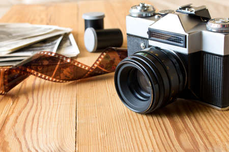 Old vintage camera, film and photos on wooden table.の写真素材