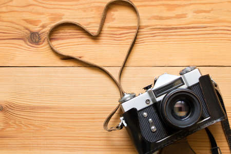 Old vintage camera on a wooden table. Heart shape.の写真素材