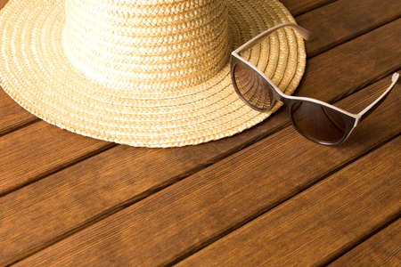Straw hat and sunglasses on wooden table. The concept of summer. Empty text space.の写真素材