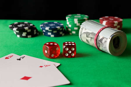 Poker chips, dice, playing cards and twisted 100 banknotes on the green table. Winning concept.