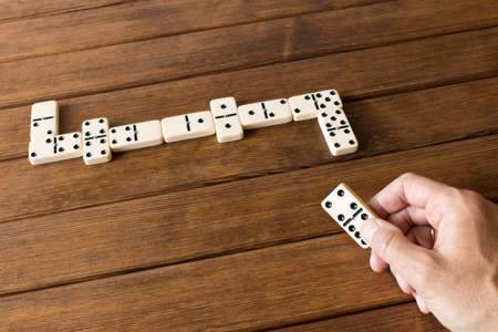 Playing dominoes on a wooden table. Man's hand with dominoesの写真素材